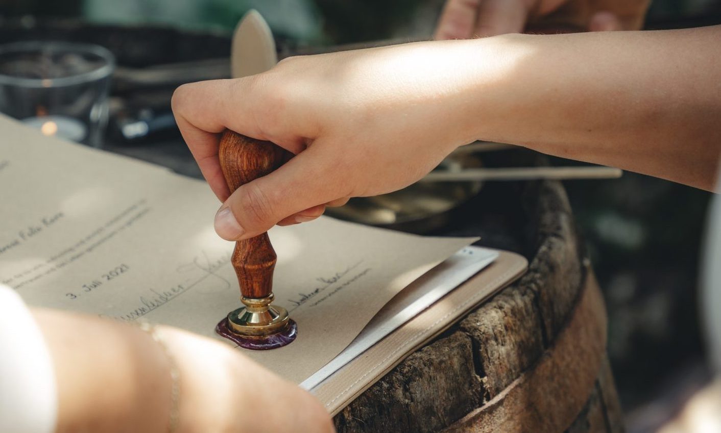 Person drückt einen Stempel auf ein Blatt Papier