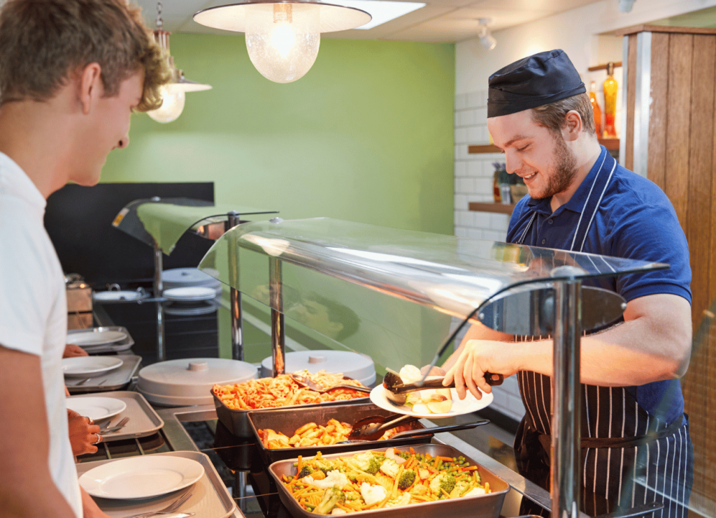 Koch gibt Essen in einer Kantine auf